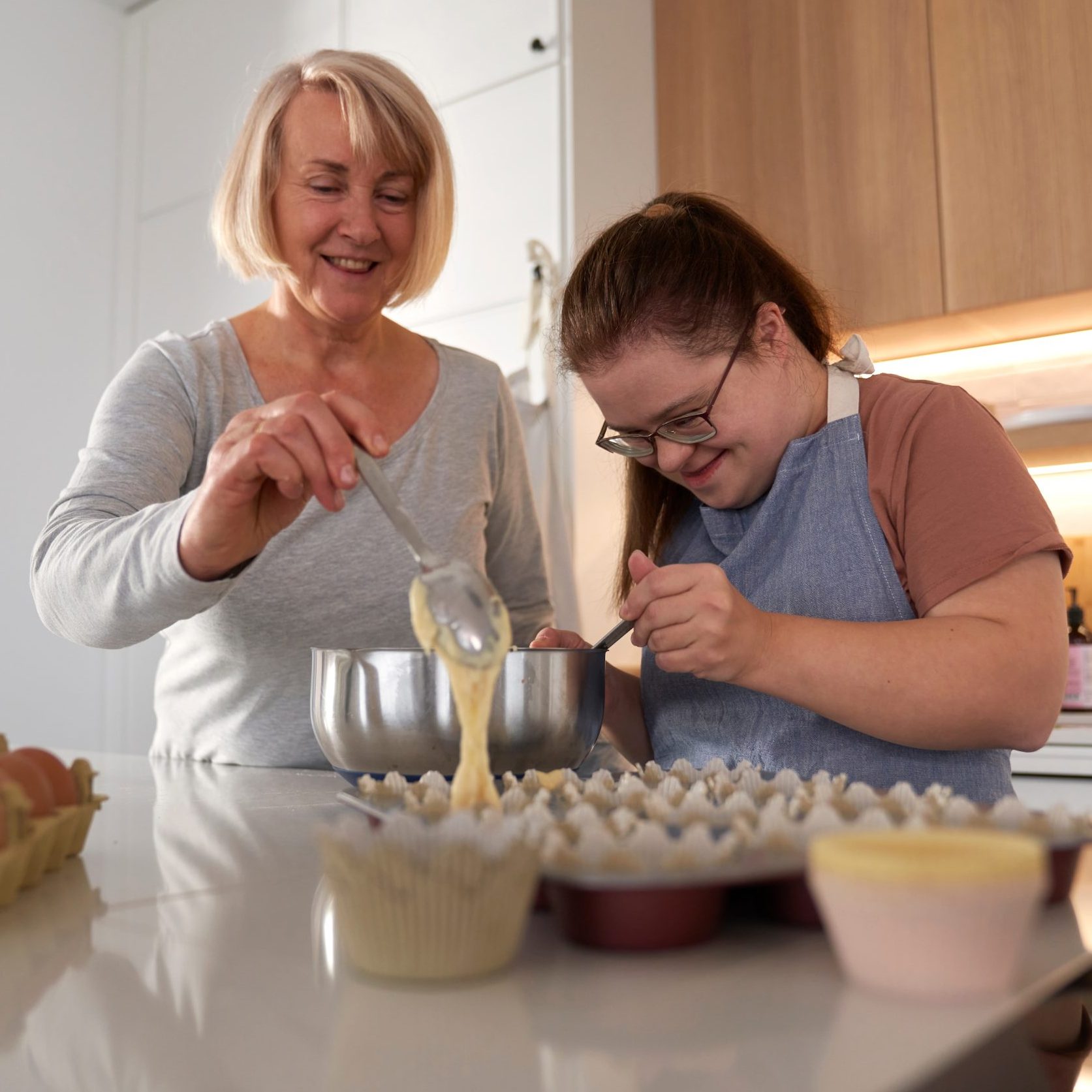 Down,Syndrome,Woman,And,Her,Mother,Making,Homemade,Cupcakes