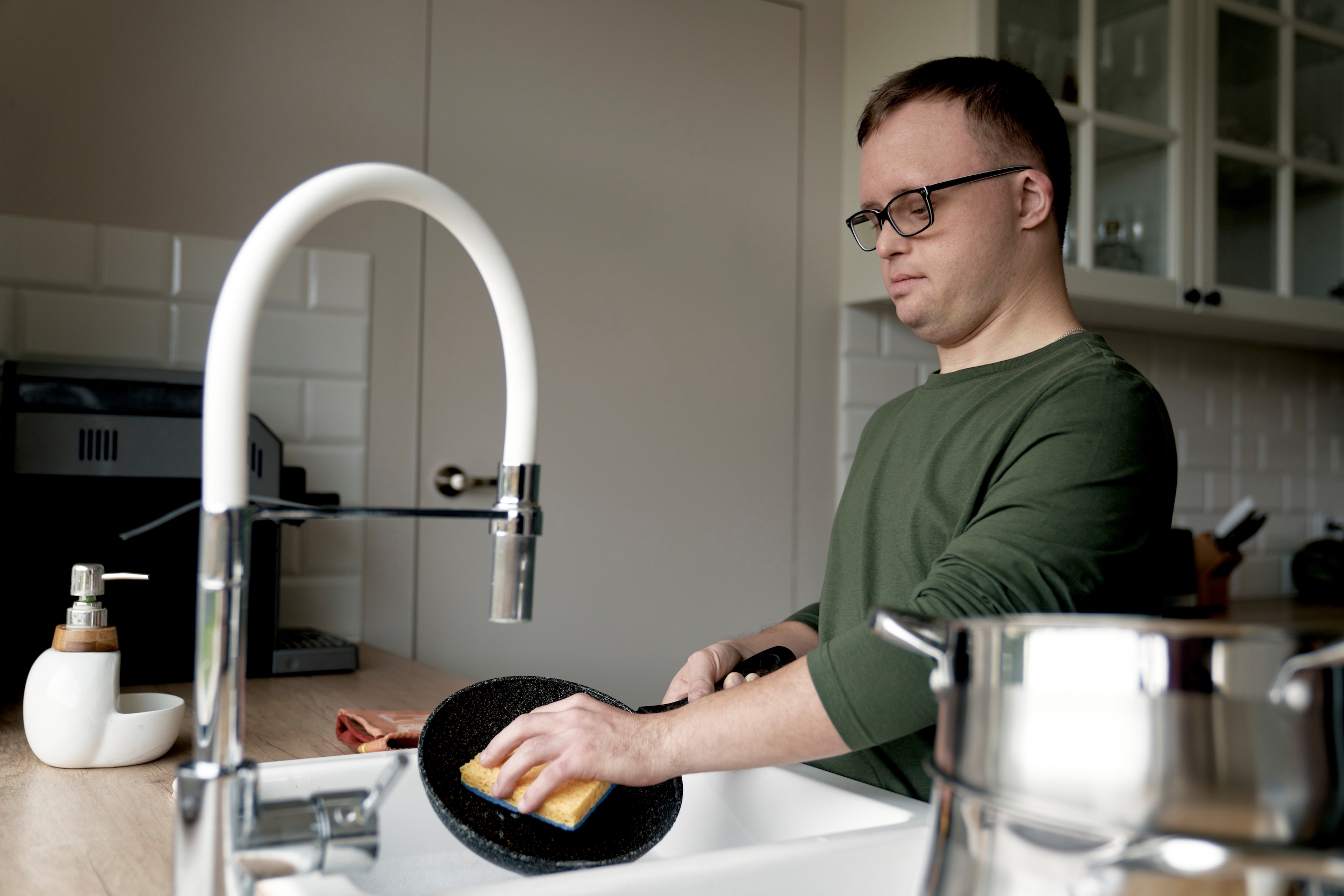 Adult,Caucasian,Man,With,Down,Syndrome,Washing,Dishes,At,Home